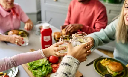 Händer som skålar med vatten över ett matbord